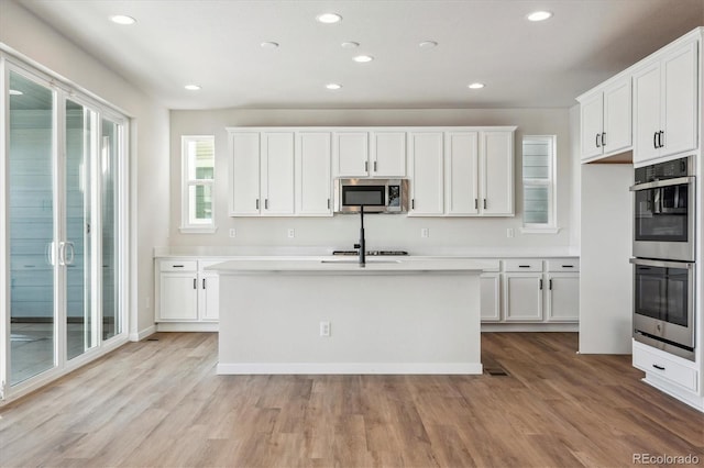 kitchen featuring white cabinets, light wood-type flooring, and appliances with stainless steel finishes