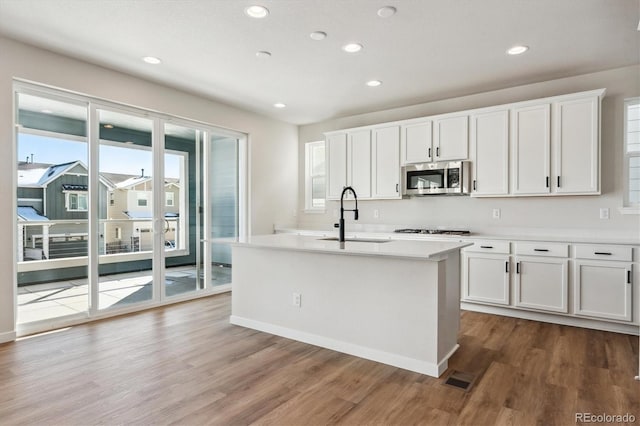 kitchen featuring white cabinets, sink, stainless steel appliances, and a kitchen island with sink