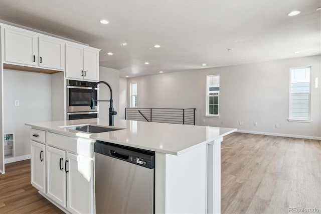 kitchen with a center island with sink, white cabinets, stainless steel appliances, and sink