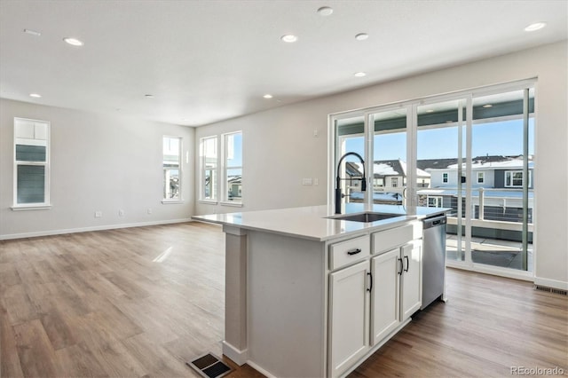 kitchen featuring white cabinets, a kitchen island with sink, sink, light hardwood / wood-style flooring, and dishwasher