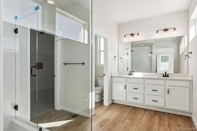 bathroom with vanity, hardwood / wood-style flooring, toilet, and a shower with door