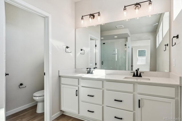 bathroom featuring vanity, toilet, a shower with shower door, and wood-type flooring