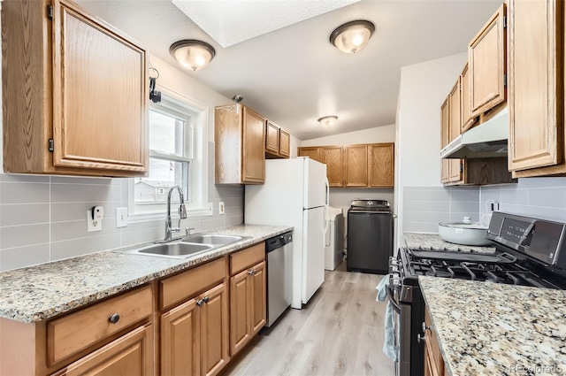 kitchen featuring appliances with stainless steel finishes, light wood-type flooring, backsplash, sink, and separate washer and dryer