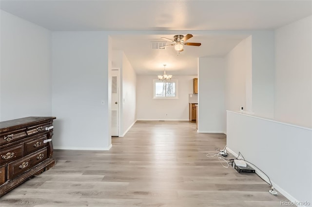 spare room featuring ceiling fan with notable chandelier and light hardwood / wood-style floors