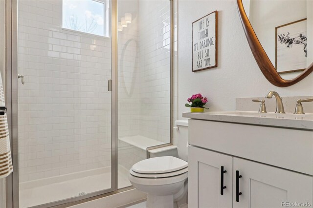 bathroom with vanity, toilet, and a shower stall