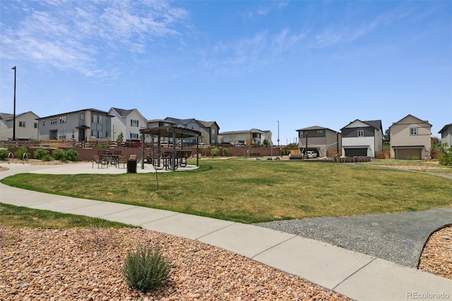 view of property's community with a pergola, a lawn, and a residential view