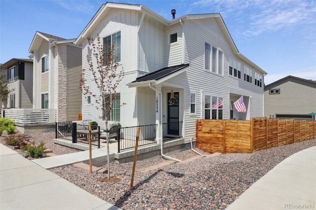 view of front of house with board and batten siding, metal roof, and fence