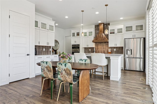 kitchen featuring custom exhaust hood, recessed lighting, decorative backsplash, and appliances with stainless steel finishes