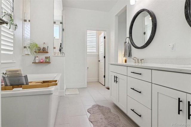 full bathroom with baseboards, tile patterned flooring, vanity, and a tub