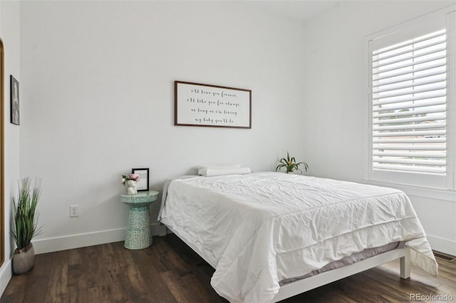 bedroom with baseboards, visible vents, and wood finished floors