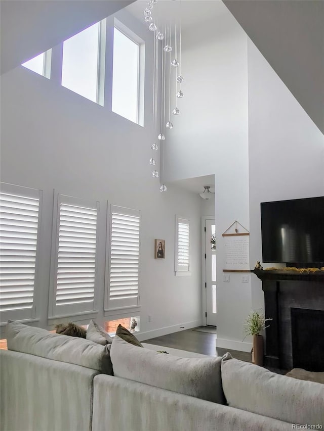 living room with a towering ceiling, baseboards, a fireplace, and wood finished floors