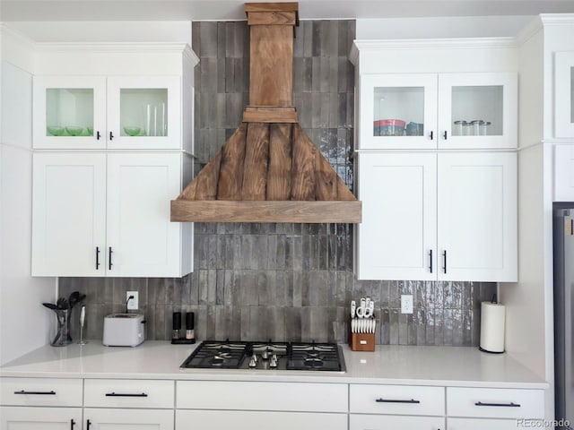 kitchen featuring gas cooktop, white cabinets, tasteful backsplash, light countertops, and glass insert cabinets