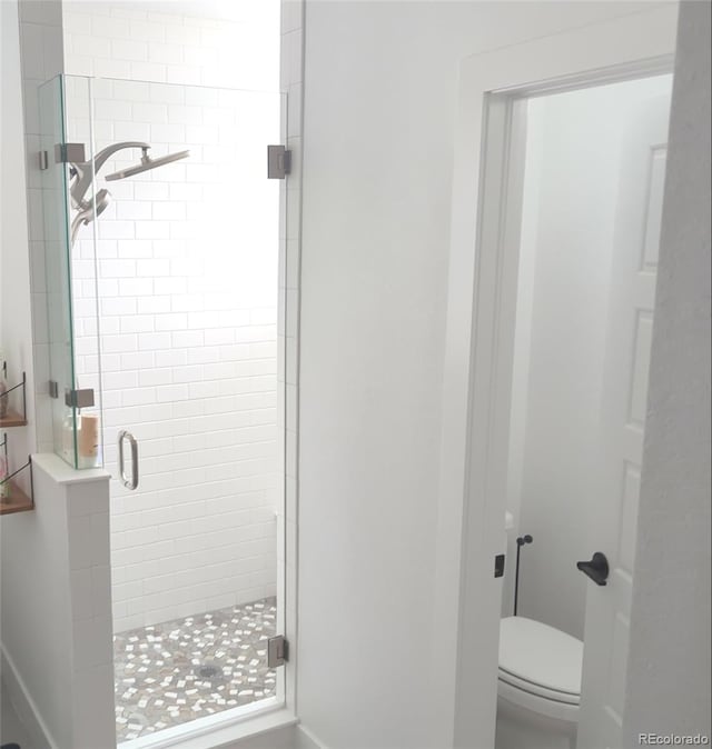 full bathroom featuring a stall shower and toilet