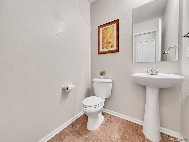 bathroom with toilet, sink, and tile patterned flooring