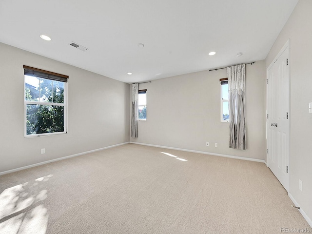 spare room with plenty of natural light and light colored carpet