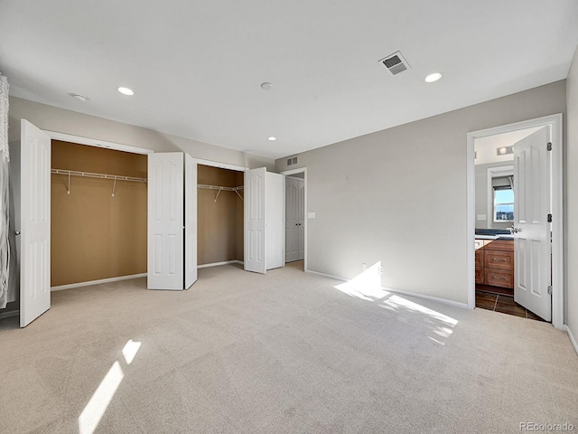 unfurnished bedroom with ensuite bath and light colored carpet