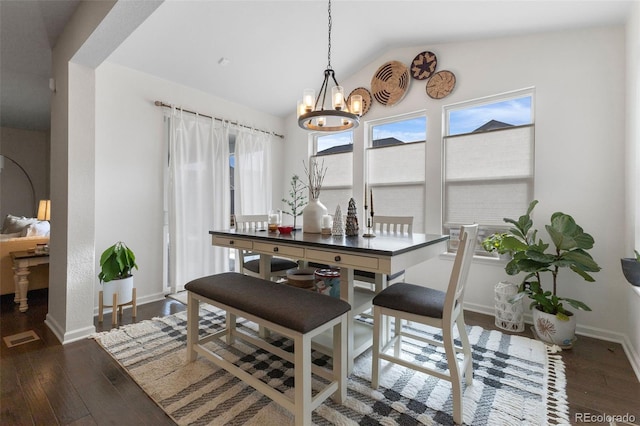 dining room with dark hardwood / wood-style flooring, vaulted ceiling, and an inviting chandelier