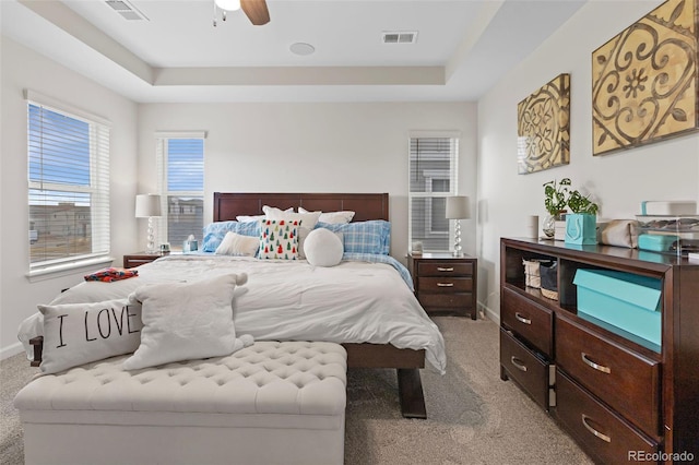 carpeted bedroom with ceiling fan and a tray ceiling