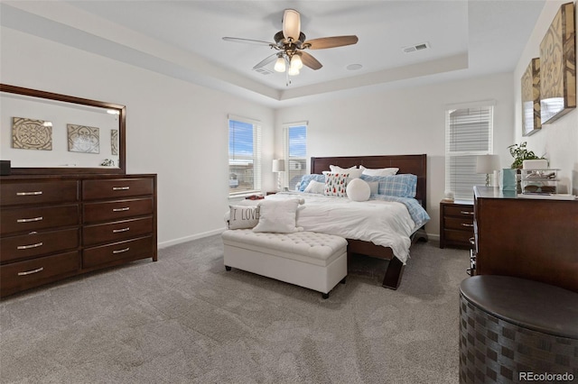 bedroom featuring carpet floors, a raised ceiling, and ceiling fan