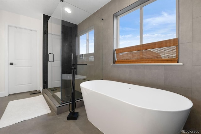 bathroom featuring tile walls and independent shower and bath