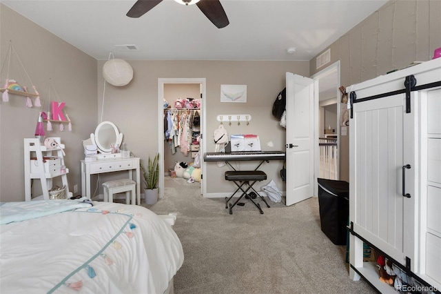 bedroom featuring ceiling fan, light colored carpet, a walk in closet, and a closet