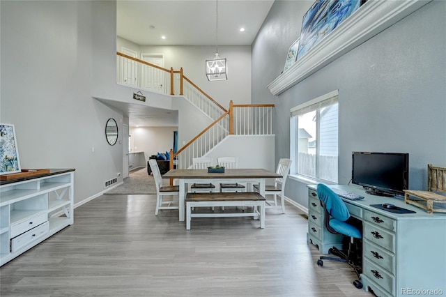 office with wood-type flooring, a high ceiling, and an inviting chandelier