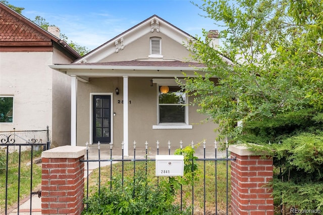 2841 Stout St, Denver, CO 80205 - view of front of property featuring stucco siding, a chimney, a fenced front yard, and covered porch