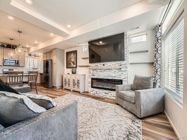 living room with a stone fireplace and light hardwood / wood-style floors