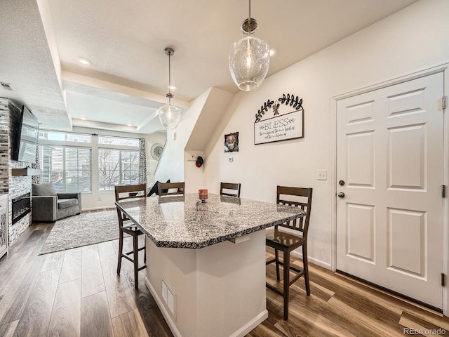 kitchen featuring pendant lighting, light stone counters, a breakfast bar area, and wood-type flooring