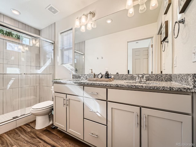 bathroom with hardwood / wood-style flooring, vanity, toilet, and walk in shower