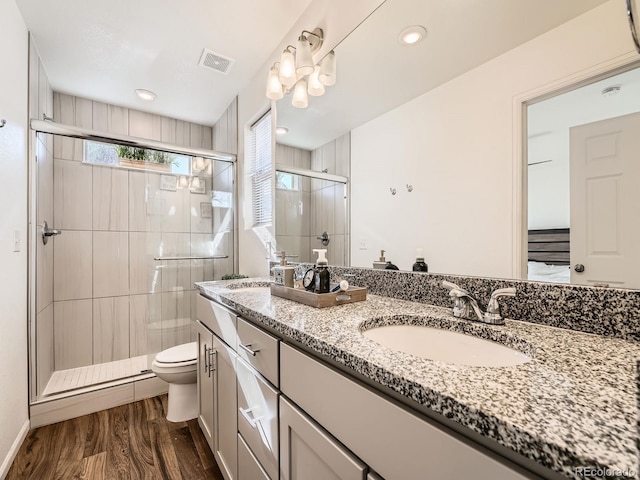 bathroom featuring hardwood / wood-style flooring, vanity, toilet, and a shower with door