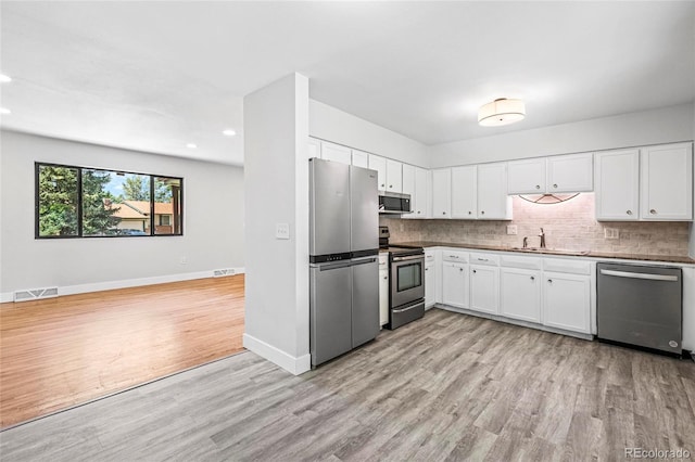 8580 Wiley Cir, Westminster, CO 80031 - kitchen featuring appliances with stainless steel finishes, recessed lighting, light wood-type flooring, decorative backsplash, and white cabinets