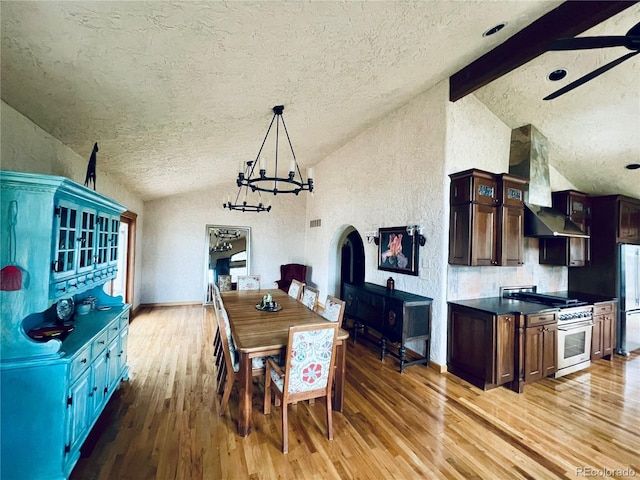 dining space featuring a textured wall, lofted ceiling with beams, wood finished floors, an inviting chandelier, and a textured ceiling