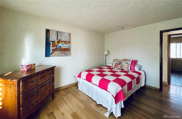 bedroom with a textured ceiling, baseboards, and wood finished floors