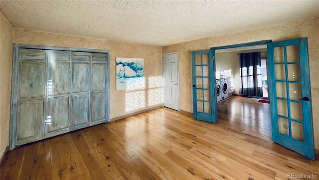 unfurnished room with wood-type flooring, baseboards, french doors, and washing machine and clothes dryer