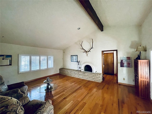 living area with vaulted ceiling with beams, a fireplace, baseboards, and wood finished floors