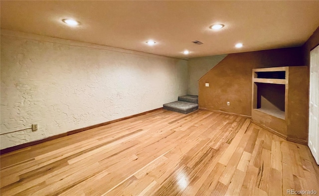 unfurnished room featuring recessed lighting, visible vents, a textured wall, wood finished floors, and stairs