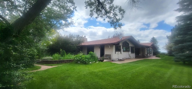 7194 S Himalaya Way, Centennial, CO 80016 - back of property with stucco siding, a lawn, a patio area, and a chimney