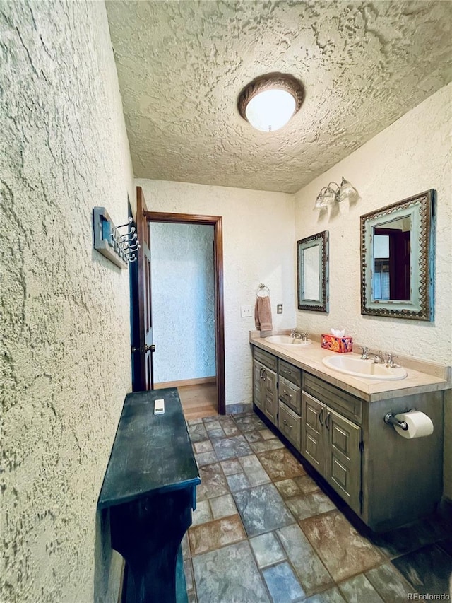 7194 S Himalaya Way, Centennial, CO 80016 - bathroom with a textured wall, double vanity, a textured ceiling, and stone finish flooring