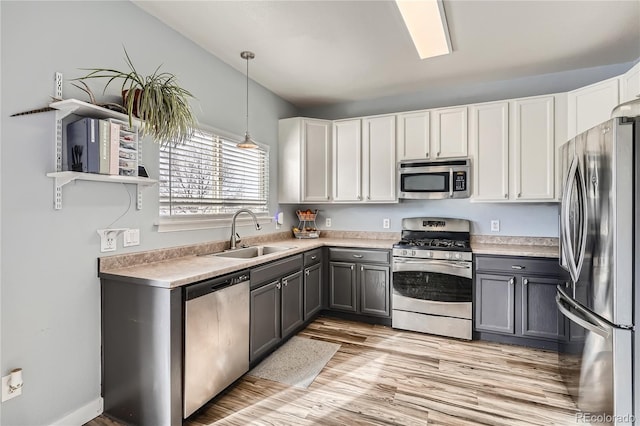 kitchen featuring gray cabinetry, white cabinets, hanging light fixtures, sink, and appliances with stainless steel finishes