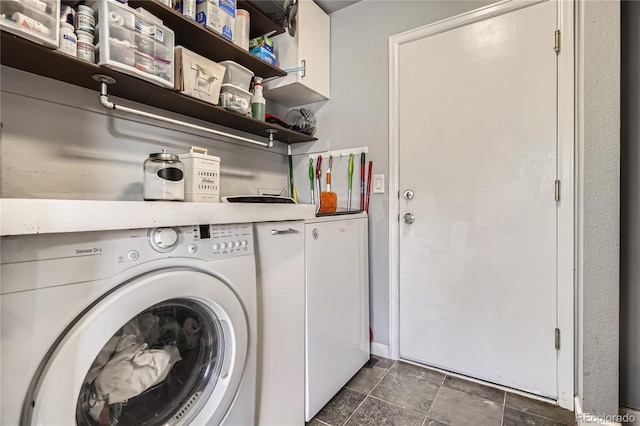 clothes washing area featuring cabinets and washing machine and clothes dryer