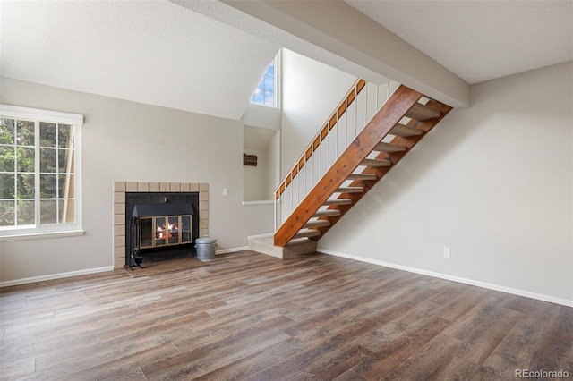 13873 E Lehigh Ave Unit B, Aurora, CO 80014 - unfurnished living room with stairway, wood finished floors, a fireplace, healthy amount of natural light, and high vaulted ceiling