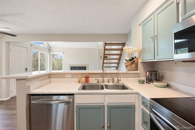 13873 E Lehigh Ave Unit B, Aurora, CO 80014 - kitchen with appliances with stainless steel finishes, a peninsula, a textured ceiling, dark wood finished floors, and light countertops