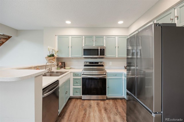 13873 E Lehigh Ave Unit B, Aurora, CO 80014 - kitchen featuring stainless steel appliances, a peninsula, dark wood-style floors, light countertops, and a textured ceiling