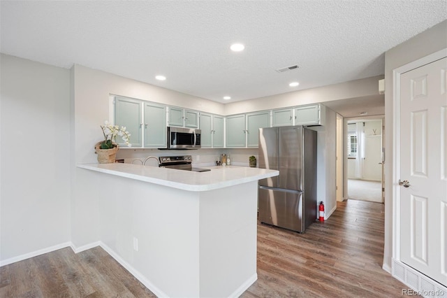 13873 E Lehigh Ave Unit B, Aurora, CO 80014 - kitchen featuring stainless steel appliances, light countertops, wood finished floors, a peninsula, and recessed lighting
