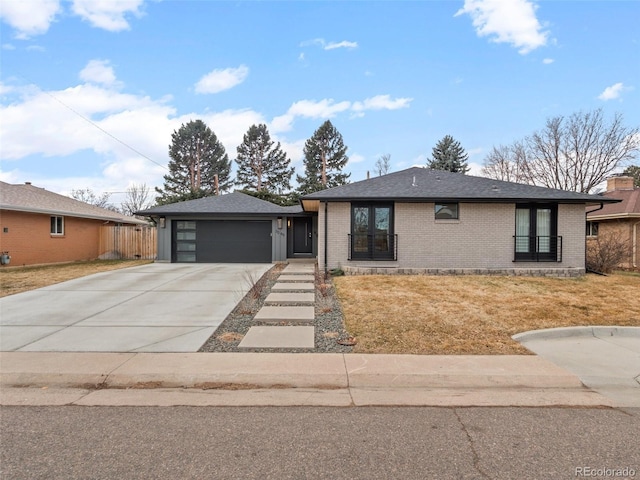 view of front of house with brick siding, concrete driveway, roof with shingles, an attached garage, and a front yard