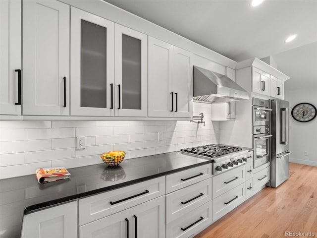 3049 S Vine St, Denver, CO 80210 - kitchen with wall chimney range hood, stainless steel appliances, dark countertops, glass insert cabinets, and white cabinets
