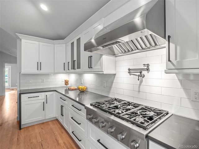 3049 S Vine St, Denver, CO 80210 - kitchen with stainless steel gas stovetop, wall chimney exhaust hood, white cabinetry, tasteful backsplash, and vaulted ceiling