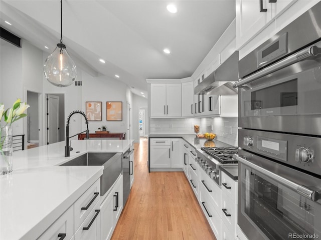 3049 S Vine St, Denver, CO 80210 - kitchen with vaulted ceiling, a sink, under cabinet range hood, backsplash, and white cabinetry