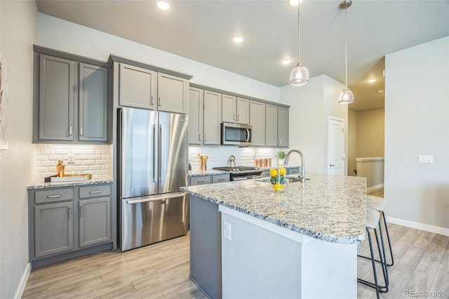12574 Lake View St, Longmont, CO 80504 - kitchen with appliances with stainless steel finishes, gray cabinets, light wood-type flooring, a kitchen breakfast bar, and recessed lighting